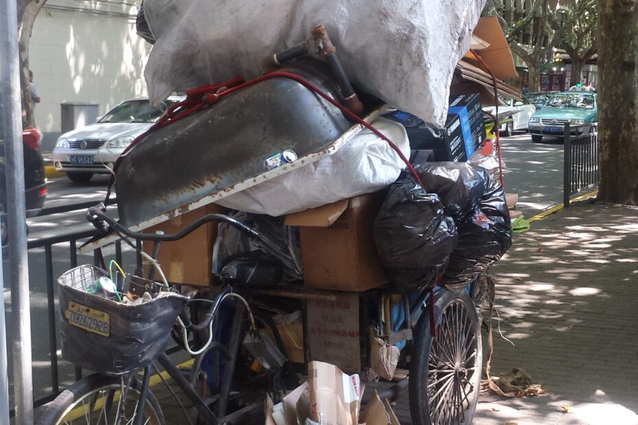 Tricycle parks on a sidewalk with personal belongings.