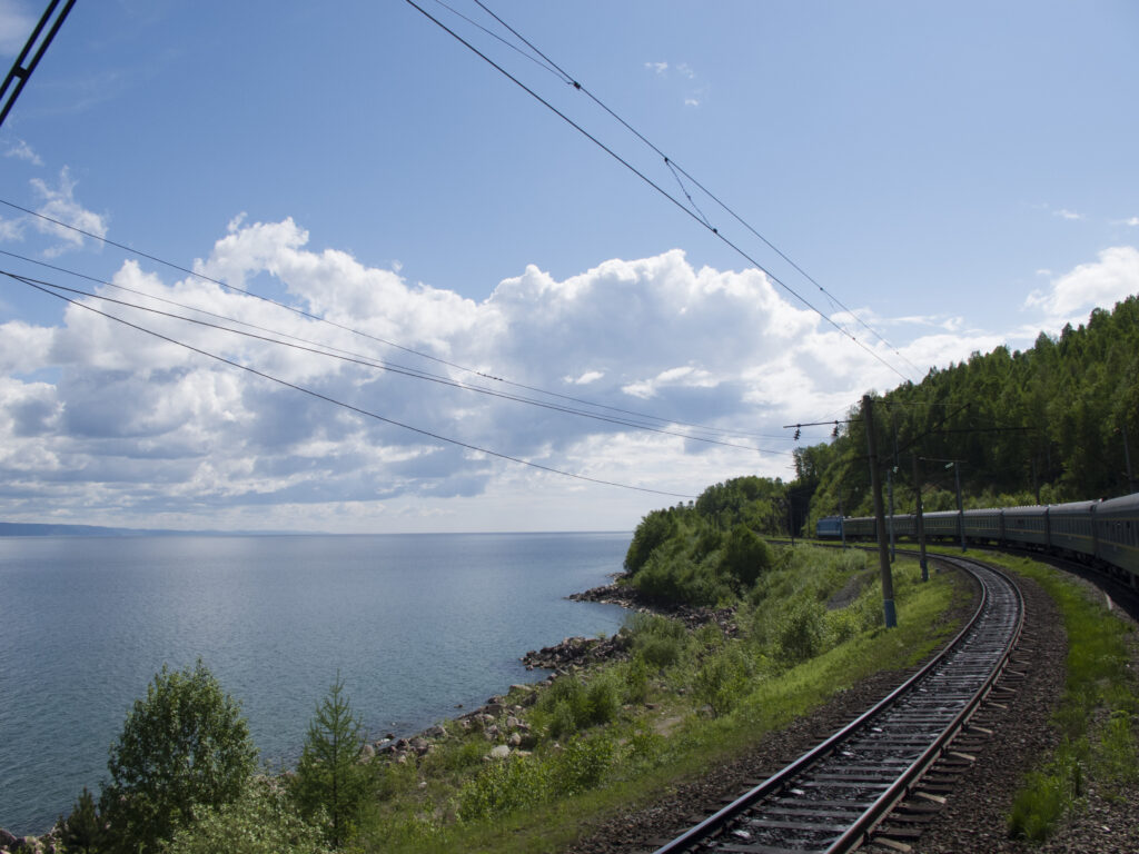 Train and tracks next to a lake